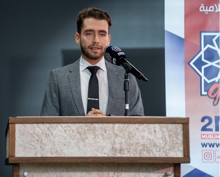 A person standing at a podium with a microphone

AI-generated content may be incorrect.