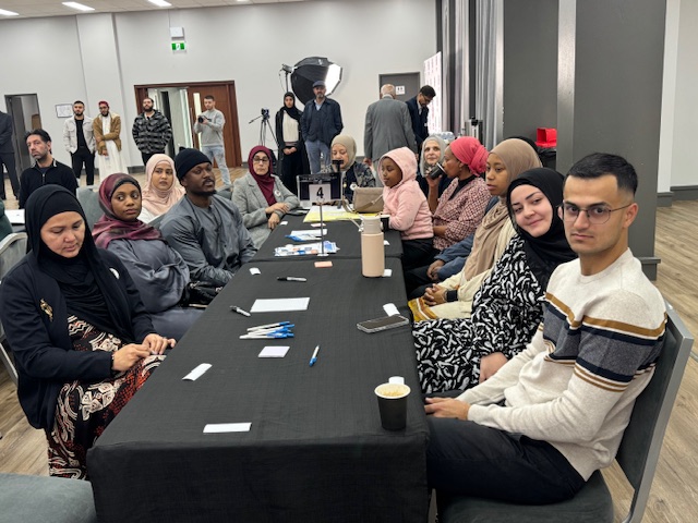 A group of people sitting at a table

AI-generated content may be incorrect.