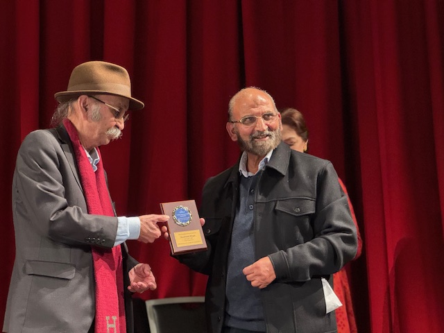 A person holding a plaque to another person

AI-generated content may be incorrect.