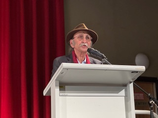 A person standing at a podium with a microphone

AI-generated content may be incorrect.