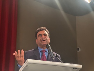 A person standing at a podium with a microphone

AI-generated content may be incorrect.