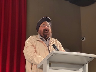 A person standing at a podium with a microphone

AI-generated content may be incorrect.