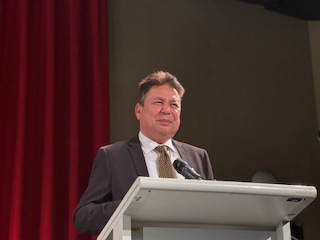 A person standing at a podium with a microphone

AI-generated content may be incorrect.