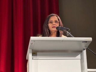 A person standing at a podium with a microphone

AI-generated content may be incorrect.