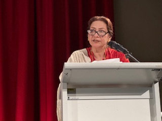 A person standing at a podium with a microphone

AI-generated content may be incorrect.