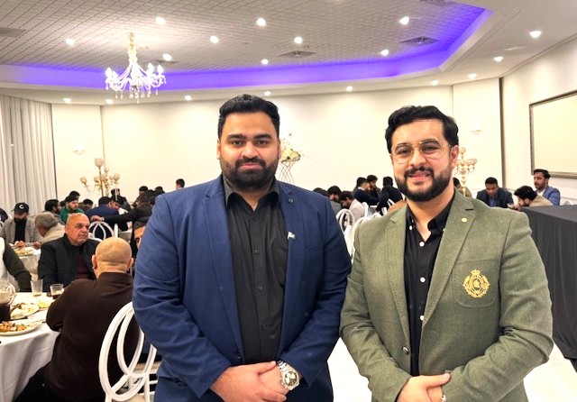 Two men standing in a room with a crowd of people

AI-generated content may be incorrect.