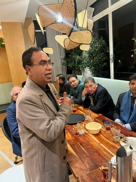 A person in a suit standing in front of a table with people around him

AI-generated content may be incorrect.