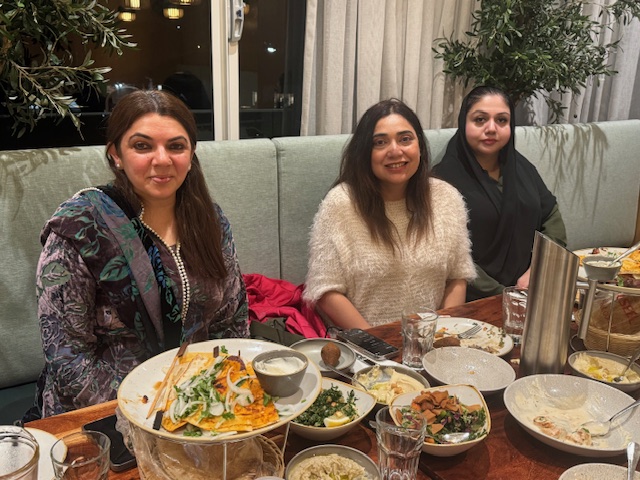 A group of women sitting at a table with food

AI-generated content may be incorrect.