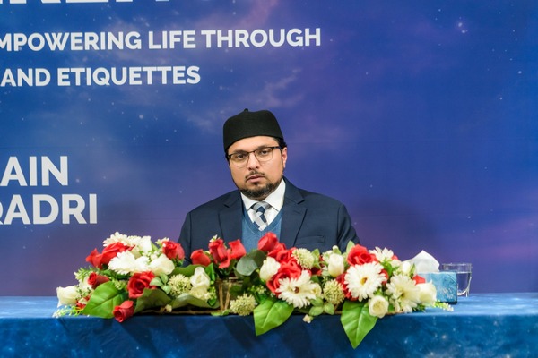 A person in a suit and tie standing behind a table with flowers

AI-generated content may be incorrect.