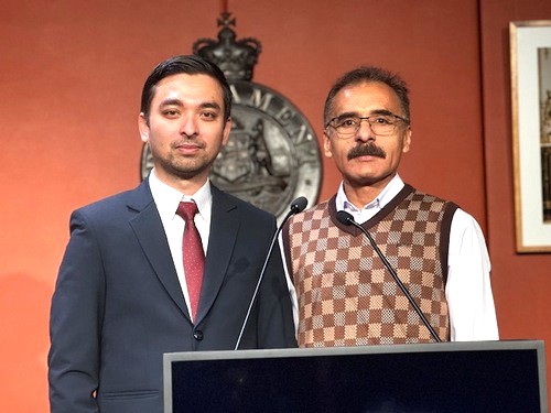 A person standing next to another person standing at a podium

AI-generated content may be incorrect.