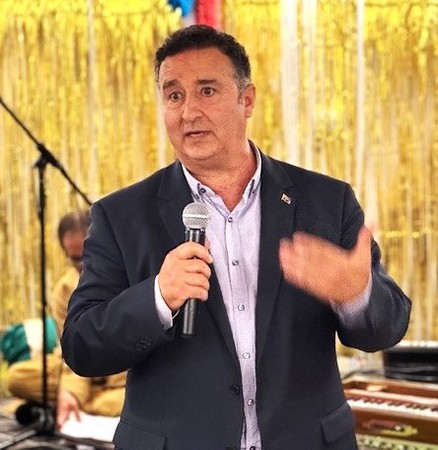 A person in a suit holding a microphone

AI-generated content may be incorrect.