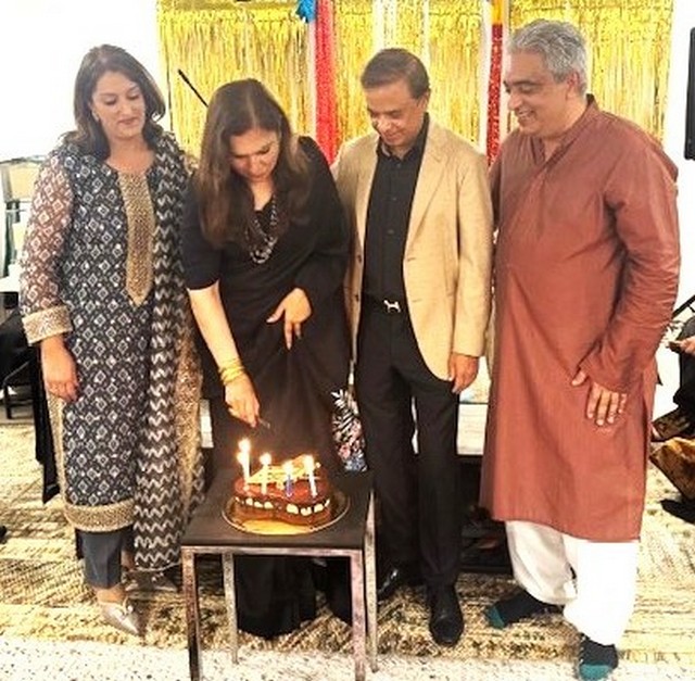 A group of people standing around a cake with candles

AI-generated content may be incorrect.