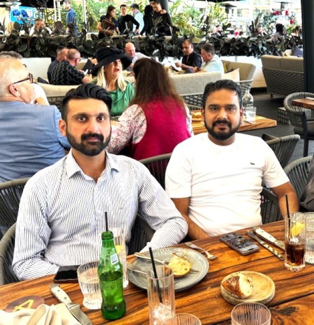 Two men sitting at a table with food and drinks

AI-generated content may be incorrect.