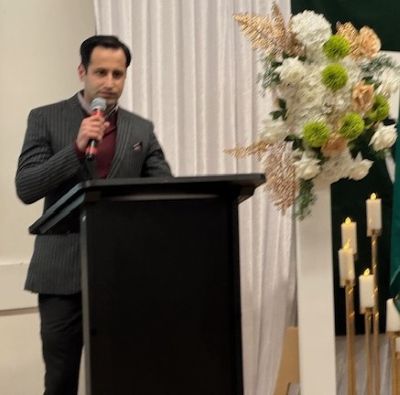 A person standing at a podium with a microphone

AI-generated content may be incorrect.