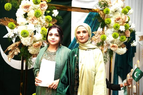 A couple of women standing in front of flowers

AI-generated content may be incorrect.