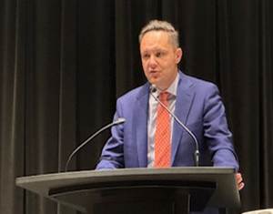 A person standing at a podium with microphones

AI-generated content may be incorrect.