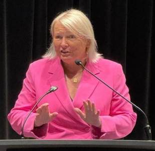 A person in a pink suit speaking into a microphone

AI-generated content may be incorrect.