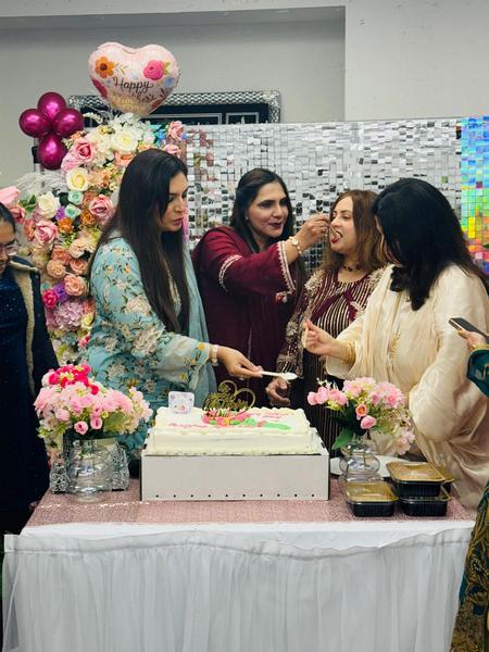 A group of women standing around a cake

AI-generated content may be incorrect.