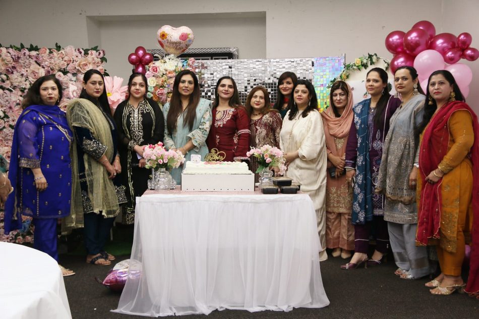 A group of women standing in front of a table with a cake

AI-generated content may be incorrect.