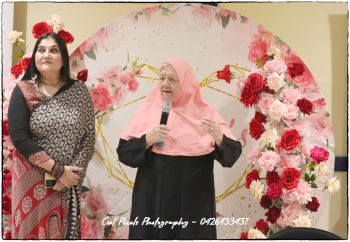 Two women standing in front of a flower backdrop

AI-generated content may be incorrect.