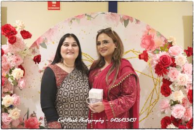 Two women standing together in front of a floral backdrop

AI-generated content may be incorrect.