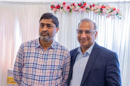 Two men standing together in front of a flowered backdrop

AI-generated content may be incorrect.
